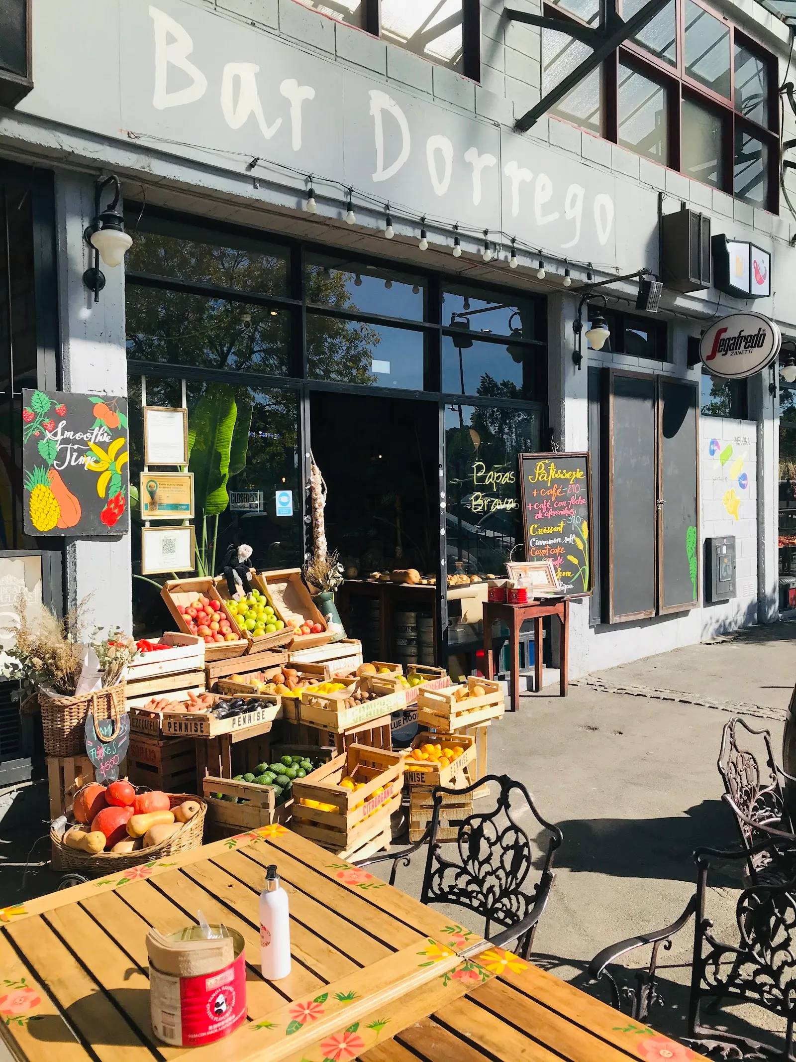 Frente de Bar Dorrego con sus cajones de fruta y mesas al sol