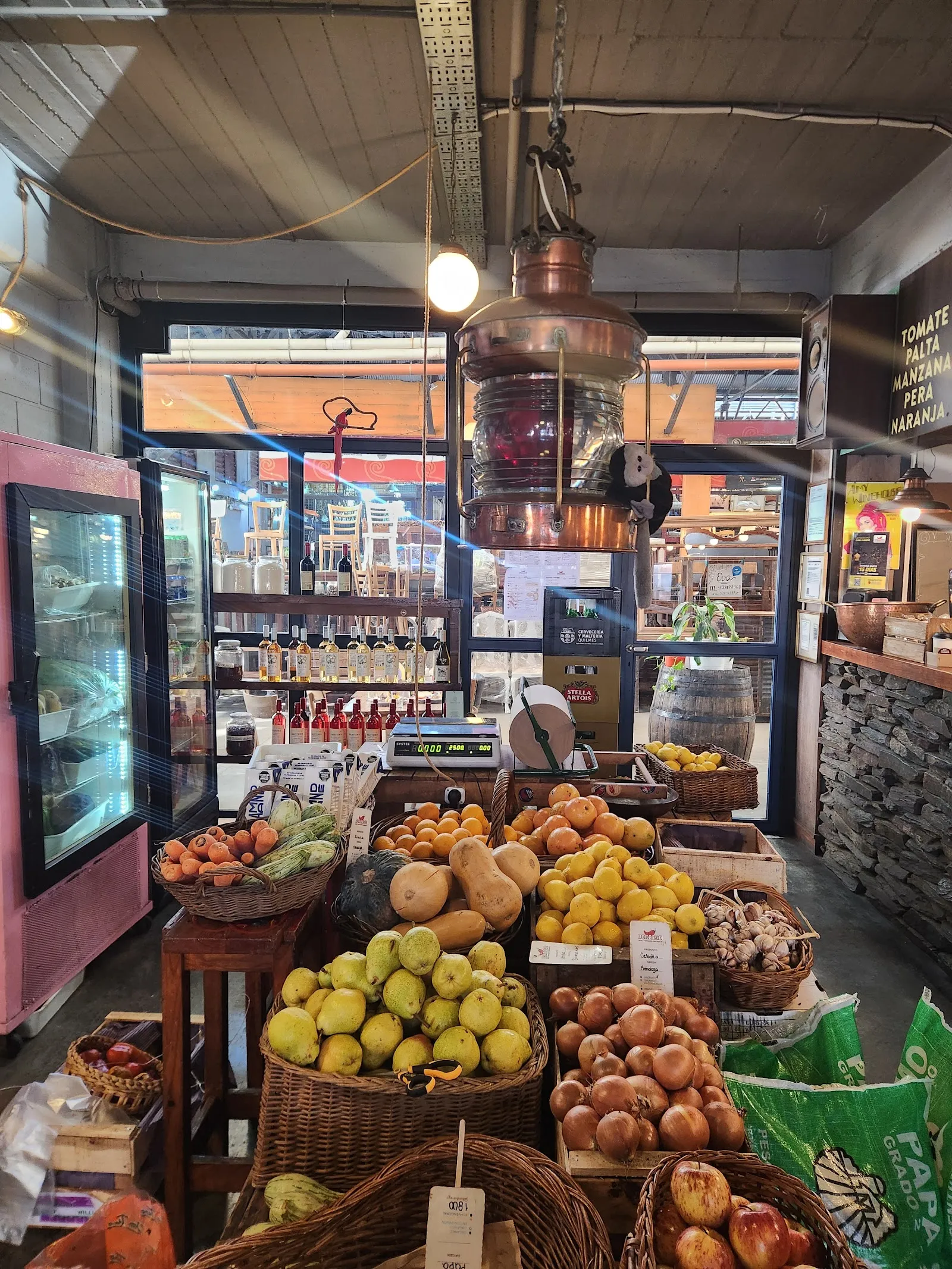 Interior del mercado con frutas frescas y una lámpara de cobre
